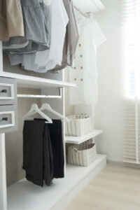 White wardrobe with shirts and pants hanging