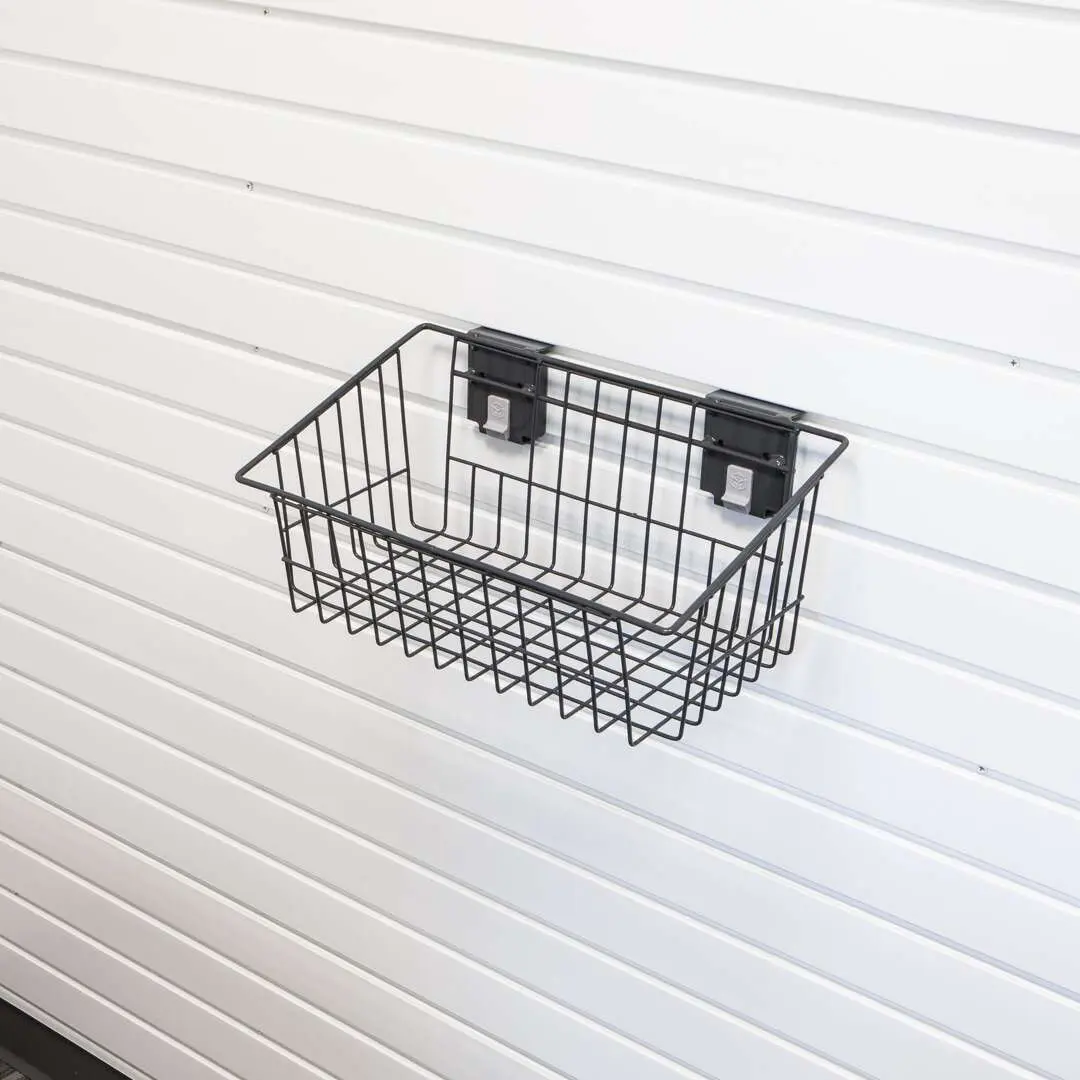 A black metal wire basket is mounted on a white slatwall using two black brackets, making it an ideal addition to closet systems or reach in closet setups from Closet Concepts. Closet Concepts of Grand Rapids