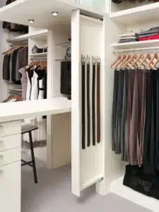A modern walk-in closet with organized clothes, shelves, drawers, handbags, and a pull-out rack holding several belts showcases smart closet concepts for effortless organization. Closet Concepts of Grand Rapids