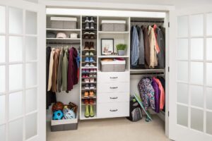 A neatly organized walk-in closet features shelves, drawers, jackets, shirts, shoes, baskets, and sports equipment arranged with efficient closet systems. Closet Concepts of Grand Rapids