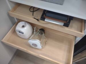 Two open kitchen drawers; the top holds an electric grill, while the bottom stores a blender base with its jar—an organized setup reminiscent of efficient closet systems. Closet Concepts of Grand Rapids