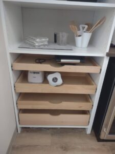 A white kitchen shelf with four open wooden drawers, perfect for organizing kitchen tools and utensils—an ideal addition to homes needing efficient closet storage or closet systems. Closet Concepts of Grand Rapids