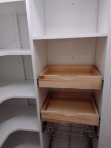 White shelving unit with two wooden pull-out drawers and several empty shelves, including curved corner shelves on the left side—an ideal addition to modern closet systems or a well-organized reach in closet. Closet Concepts of Grand Rapids