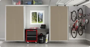 A tidy garage with storage cabinets, a red tool chest, a window, wall-mounted bicycles, and various tools and bins neatly organized for efficient closet storage. Closet Concepts of Grand Rapids