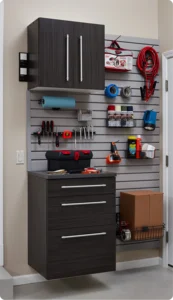 Wall-mounted storage system by Closet Concepts featuring dark cabinets, drawers, shelves, and a slat wall panel for tools and supplies—ideal for organizing a utility or garage room. Closet Concepts of Grand Rapids