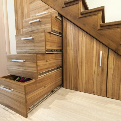 Modern architecture interior with  luxury hallway with glossy wooden stairs in modern storey house. Custom built pullout cabinets on glides in slots under stairs